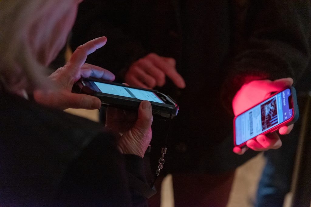 An usher scans a ticket from a cell phone.