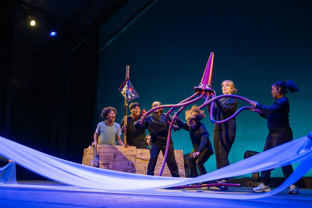 High school students stage a theater production on stage with a pirate ship and an octopus